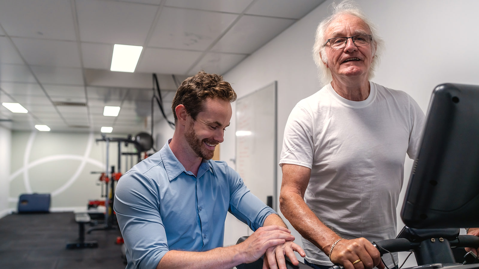 Physiotherapist coaching a patient on an exercise bike during concussion exercise rehabilitation