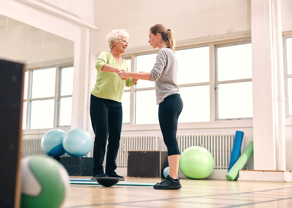 Physiotherapist supporting a patient on a balance board during vestibular rehabilitation